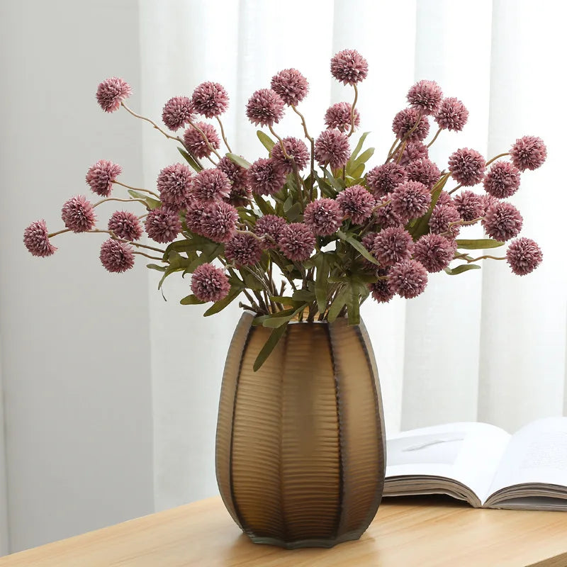Dark pink artificial dandelion stems in bronze vase
