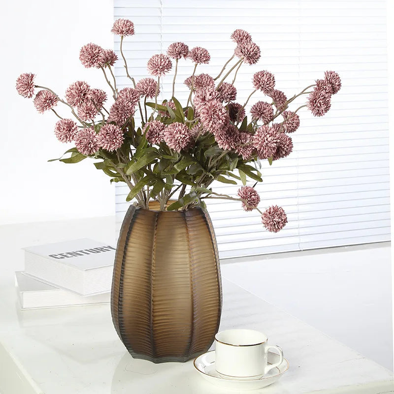 Mauve artificial dandelion stems in bronze vase